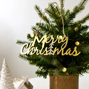 Golden Merry Christmas wooden hanging ornament on a lit tree in a cozy home setting