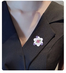 Detail of atom structure brooch with pink rose on a black suit lapel
