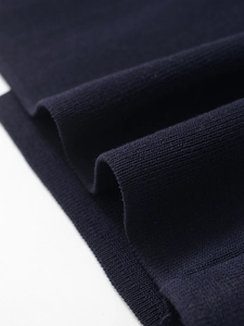 Macro shot of dark blue knit fabric showing fine texture and elegant draped folds