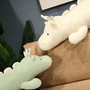 Close-up of white and green plush dragon pillows on a modern fabric sofa