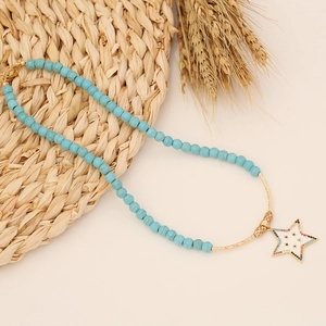 Bohemian turquoise beaded necklace featuring a colorful crystal star pendant on beige background