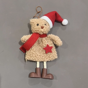 Detail of Christmas teddy bear ornament with red hat and star on gray background
