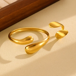 Close-up of polished gold-plated open bangle and ring set with a liquid metal design