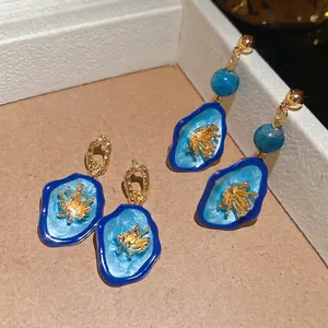 Élégantes boucles d'oreilles fleurs ovales dorées avec émail bleu et texture vintage