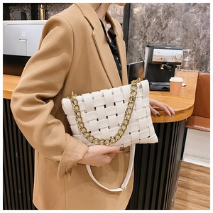 Close-up of white woven leather handbag with chunky gold chain strap on model