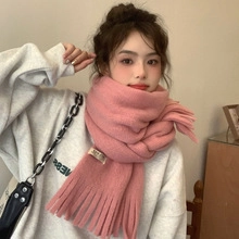 Close-up of soft pink knitted winter scarf with fringe details worn by a young model