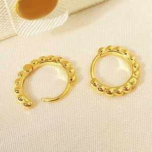 Detail view showing gold beaded hoop earrings in open and closed states on fabric