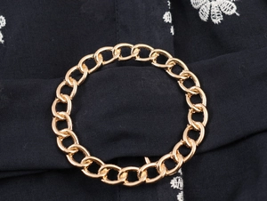Close-up detail of golden chain hardware and embroidery on vintage elegant long dress