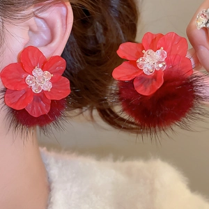 Detail shot of red acrylic flower earrings with plush pom poms and crystal center