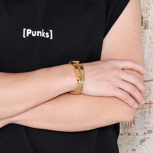 Close-up of gold razor blade bracelet in punk style on model wrist with wheat chain detail