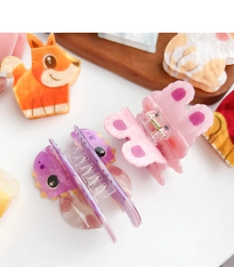 Close-up of colorful acrylic hair claws featuring various cartoon animal shapes and colors