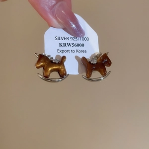 Detailed macro of a resin rocking horse earring with gold glitter and silver 925 inlay