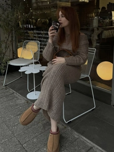 Detail of a brown ribbed knit dress paired with platform shearling slippers outdoors