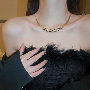 Detail view of gold curved pendant with black enamel and diamonds on snake chain
