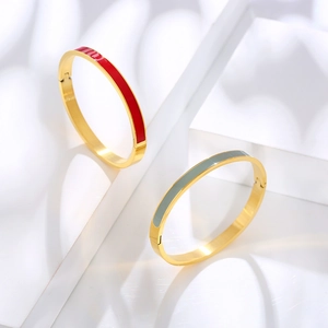 Detail view of gold stainless steel enamel bangles in red and grey on white steps