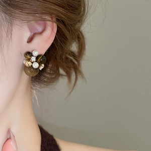 Detail view of retro earrings with dark brown beads and pearls on model ear