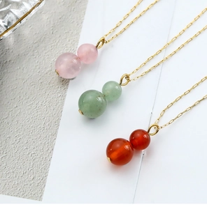 Detailed view of gourd-shaped natural agate pendants in pink, green, and orange-red colors