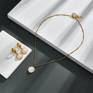 Detailed view of golden stainless steel necklace and baroque pearl earring jewelry set