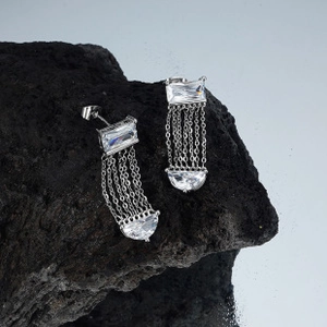 Macro shot of silver fringe earrings with cubic zirconia on black volcanic rock base