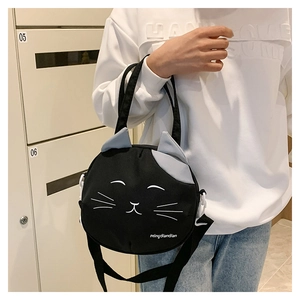 Detail of cute black cat cartoon canvas bag shown worn on a model in a casual setting