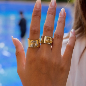 Detail of wide cherry design rings in gold and silver finish worn on a hand