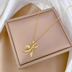 Elegant gold tulip pendant necklace with sparkling crystals on a beige jewelry box