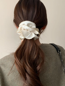 Chouchou en satin blanc avec liseré doré porté sur un chignon en lumière naturelle