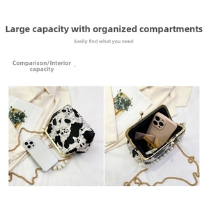 Detail of cow print crossbody bag showing gold metal frame clasp and pearl chain strap