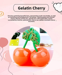 Detail of red jelly cherry keychain with green rhinestone leaves and golden ring