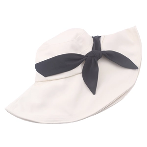 Dettaglio cappello da sole a tesa larga con grande fiocco nero su tela color crema