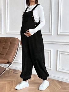 Detail view of adjustable black corduroy maternity overalls with side button accents