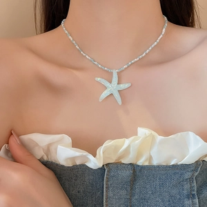 Detail of light blue resin starfish pendant and beaded necklace on a model collarbone
