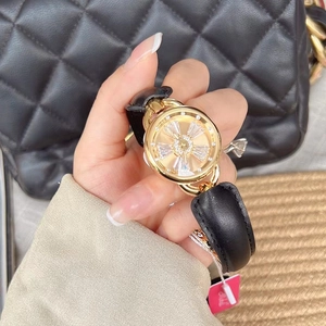 Close-up of a gold watch featuring a rotating crystal dial and a black leather strap