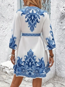 Rear view of bohemian V-neck mini dress with blue floral print and waist tie detailing