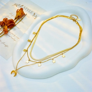Layered gold star and moon necklace set displayed on an elegant ceramic jewelry tray