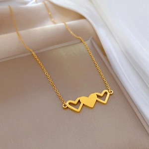 Detailaufnahme einer goldenen Titanstahlkette mit drei ineinandergreifenden Herzanhängern