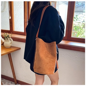 Detailed texture of brown suede tote bag with slim shoulder straps on a navy coat