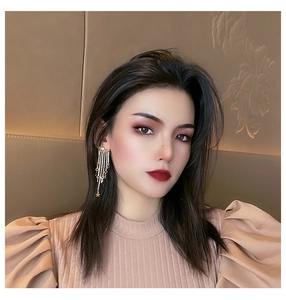 Detail shot of long golden star tassel earrings worn by a model for elegant styling