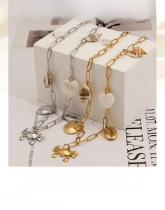 Détail de colliers océaniques dorés et argentés avec pendentifs coquillage et crabe