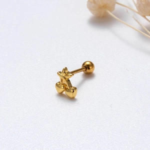 Detail of a gold cherry-shaped cartilage stud earring with cubic zirconia accents