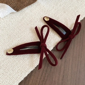 Close-up of deep red velvet bow hair clips with gold smile happy engraved metal detail