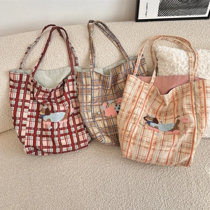 Detail of plaid canvas tote bags featuring embroidered cartoon dogs and vintage patterns