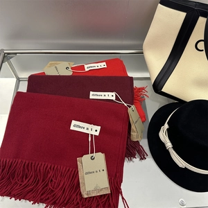 Detail of soft red cashmere-feel scarves with tassels, showing fabric texture and labels