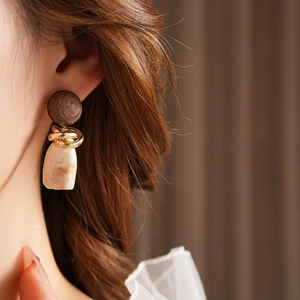 Detail of vintage geometric earrings with wood beads and resin pendants on model
