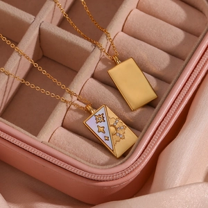 Macro view of gold rectangle pendants with sun and star engravings on white shell inlay
