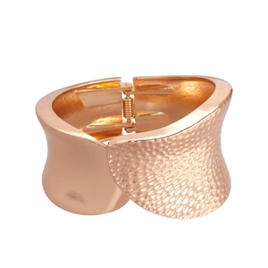 Irregular textured gold bangle with hammered finish and hinge opening on white background