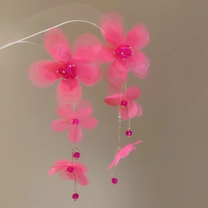 Detail of pink chiffon flower tassel earrings with delicate gold chains and soft fabric petals