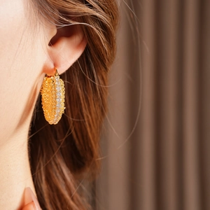Close-up of gold-plated chain hoop earring with sparkling zircon on a model's ear