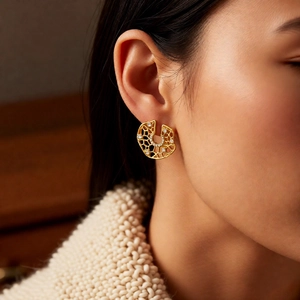 Macro detail of gold geometric hollow earrings with sparkling white zircons on model