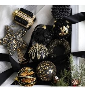 Detailed set of black and gold Christmas ornaments including glitter spheres and stars